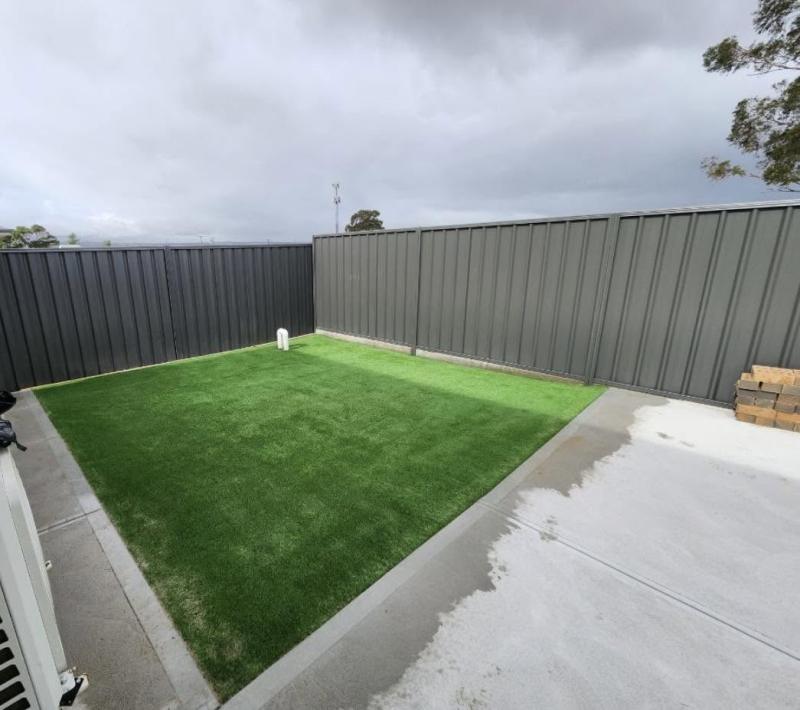 Monument Colorbond courtyard fence with an artificial turf install and concrete surround